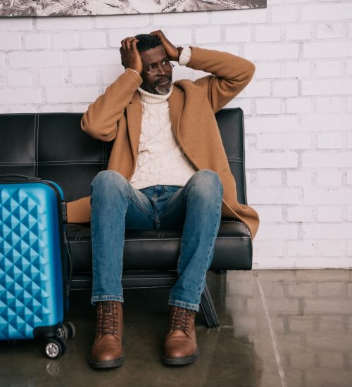 Middle aged traveler sitting on a sofa and clutching head