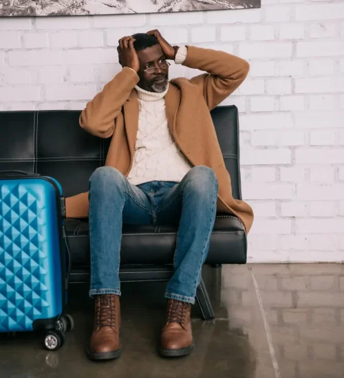 Middle aged traveler sitting on a sofa and clutching head